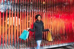 Attractive young African-American woman shopping - shopping bags, outdoors, street view, suitable for holiday shopping themes, among others photo