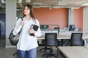 Schoolgirl standing with books and backpack at school. photo