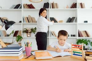 tutor deals with the preschooler with a laptop, a real home interior, the concept of childhood and learning photo