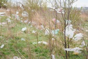 ecológico contaminación de naturaleza. el plastico bolso enredado en plantas en contra el fondo de el montañas. global ambiental contaminación. reciclaje, claro el tierra desde el plastico escombros. foto