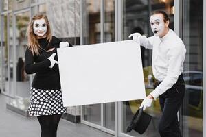 Your text here. Actors mimes holding empty white letter. Colorful portrait with gray background. April fools day photo