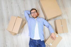 moving, people and real estate concept - happy smiling man with boxes at new home photo