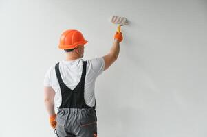 Painter using a paint roller and painting a wall isolated on white background. photo