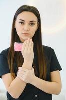 A beautiful woman, an employee of a beauty studio, holds eyebrow brushes in her hands. photo