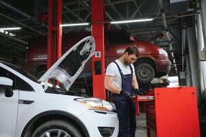 Auto mechanic working on car engine in mechanics garage. Repair service. photo