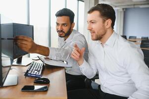 Two men traders sitting at desk at office together looking at data analysis discussing brainstorming successful strategy inspired teamwork concept close-up photo