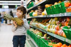 pretty boy with pineapple in supermarket photo