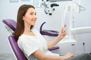 mujer mirando en el espejo y sonriente después chequeo a dentista oficina. foto