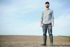 un joven granjero inspecciona el calidad de trigo coles en el campo. el concepto de agricultura. foto