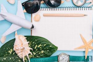 Preparation for Traveling concept, watch, airplane, money, passport, pencils, book, Photo frame, eyeglass on blue background with copy space.