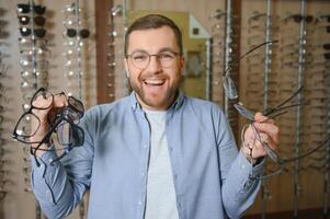 Young man choosing spectacles at optic shop photo