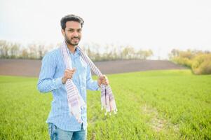 Portrait of farmer standing in a wheat field. farmer stands in green wheat field, looks, examines his crop photo