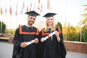 un multirracial grupo de graduados indio masculino graduado y europeo hembra estudiante contento con diplomas en manos. foto