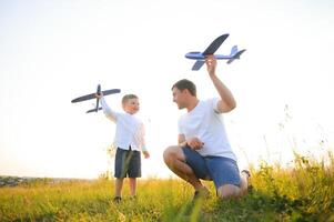 Dad with his son at sunset in nature. A father plays with toy airplanes with his son at sunset. father's day photo