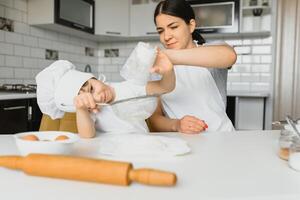 Son and mother preparing dough together photo