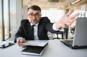 enojado empresario sentado a el mesa y gritando encima. foto