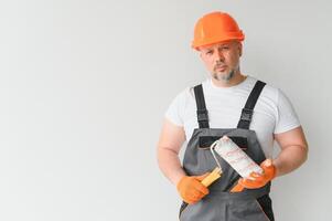 hombre estar en el habitación con pintar rodillo en su mano foto