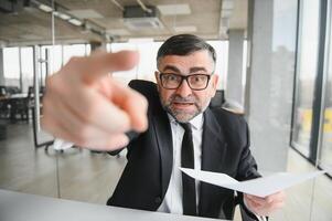 Angry businessman sitting at the table and screaming over. photo