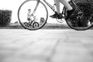 niños en un bicicleta a asfalto la carretera en temprano Mañana. pequeño chico aprende a paseo un bicicleta en el parque. contento sonriente niño, montando un ciclismo. foto