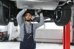 Adult man in blue colored uniform works in the automobile salon. photo