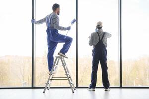 multiethnic professional cleaners in uniform washing large windows in office photo