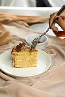 Salted Caramel Blondie cake slice include chocolate cream, sugar with fork, cup of coffee and pot served plate isolated on napkin side view of cafe food photo