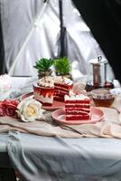 Premium Red Velvet cake and slice include cream, sugar with fork, cup of coffee and pot served on board isolated on napkin side view of cafe food photo