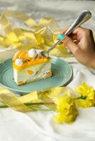 Mango Yogurt Cake slice topping with pistachio fork and flowers served in plate isolated on napkin side view cafe bake food photo