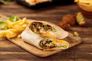 Falafel wrap shawarma with fries served in a cutting board isolated on wooden table background side view of fastfood photo