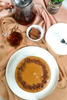 Salted Caramel Blondie cake include chocolate cream, sugar with fork, cup of coffee and pot served on board isolated on napkin top view of cafe food photo