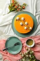 Mango Yogurt Cake topping with pistachio fork and flowers served in plate isolated on napkin top view cafe bake food photo