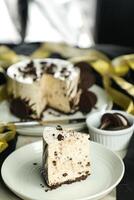 Oreo Cheesecake slice include chocolate, cream, sugar with fork and flowers served in plate isolated on napkin side view of cafe food photo