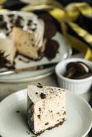 Oreo Cheesecake slice include chocolate, cream, sugar with fork and flowers served in plate isolated on napkin side view of cafe food photo