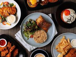 A breakfast fast food table Pan Fried Wild Cod Fish, Kimchi Fried Rice, Wing Zing, Fish And Chips, Caramel Latte, Eggs Blackstone, top view food photo
