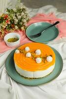 Mango Yogurt Cake topping with pistachio fork and flowers served in plate isolated on napkin side view cafe bake food photo