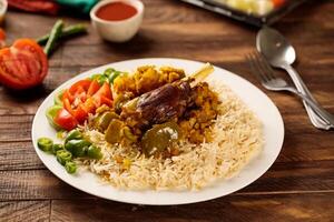 Beef biryani with pickle, salad and tomato sauce served in a dish isolated on wooden table background side view of fastfood photo