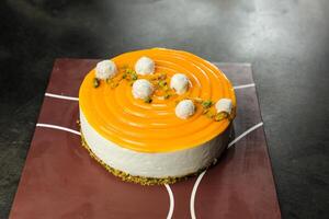 Mango Yogurt Cake topping with pistachio fork and flowers served in plate isolated on napkin side view cafe bake food photo