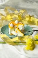 Mango Yogurt Cake slice topping with pistachio fork and flowers served in plate isolated on napkin side view cafe bake food photo