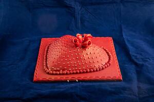 Heart Shaped red Cake with rose flowers, knife and fork served on board isolated on napkin side view of cafe baked food photo