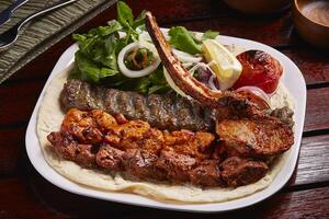 picante mezclado parrillas plato con tikka bota kebab, ensalada, limón y un pan servido en plato aislado en mesa lado ver de medio este comida foto