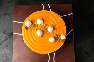 Mango Yogurt Cake topping with pistachio fork and flowers served in plate isolated on napkin top view cafe bake food photo