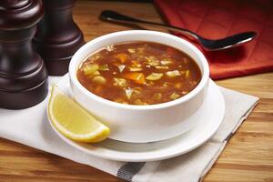 Hot Hot and Sour with Vegetable or Prawns soup with lemon slice served in bowl isolated on table side view of middle east food photo