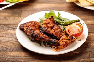 Grilled chicken with tomato and salad served in a dish isolated on wooden table background side view of fastfood photo