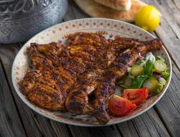 grilled whole chicken served in dish side view on wooden table background photo