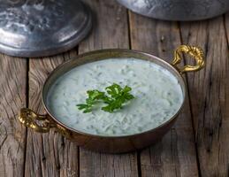 Fresco Pepino yogur raita servido en plato lado ver en de madera mesa antecedentes foto