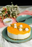 Mango Yogurt Cake topping with pistachio fork and flowers served in plate isolated on napkin side view cafe bake food photo