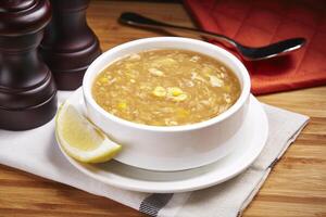 Hot chicken Corn Soup with lime slice served in a dish isolated on table side view of middle east food photo