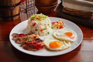 Brunch breakfast with chicken, fried rice and eggs served in a dish isolated on wooden background side view photo