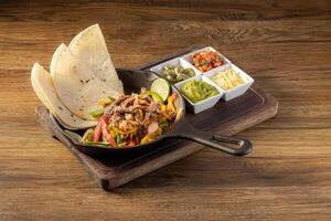 Mexican Beef fajita with bell peppers, grilled vegetables and onions top view on dark wooden background photo