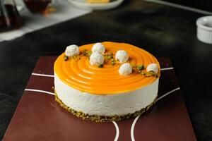 Mango Yogurt Cake topping with pistachio fork and flowers served in plate isolated on napkin side view cafe bake food photo